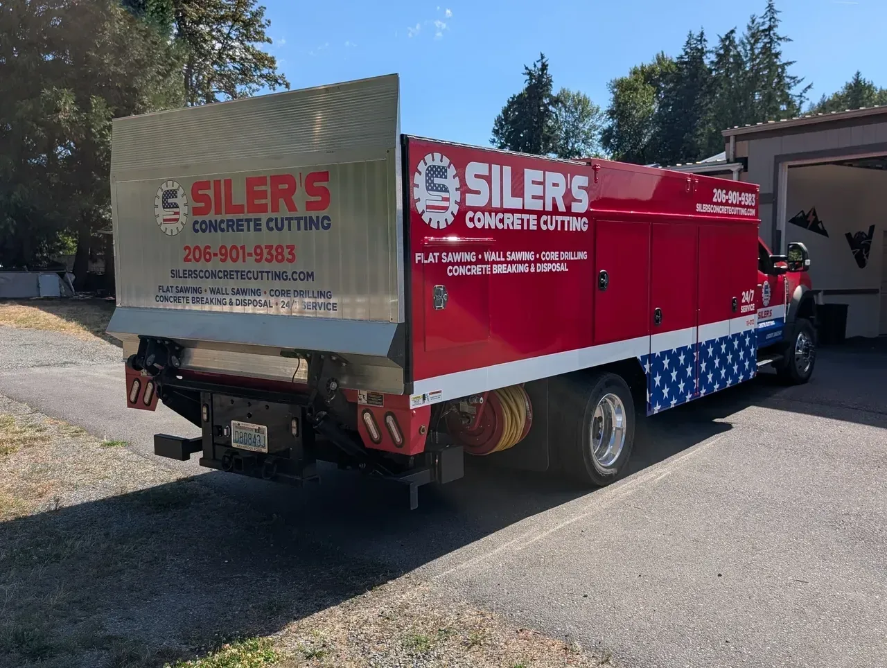 Red Silers pickup truck with enclosed cargo box parked in a driveway near a house