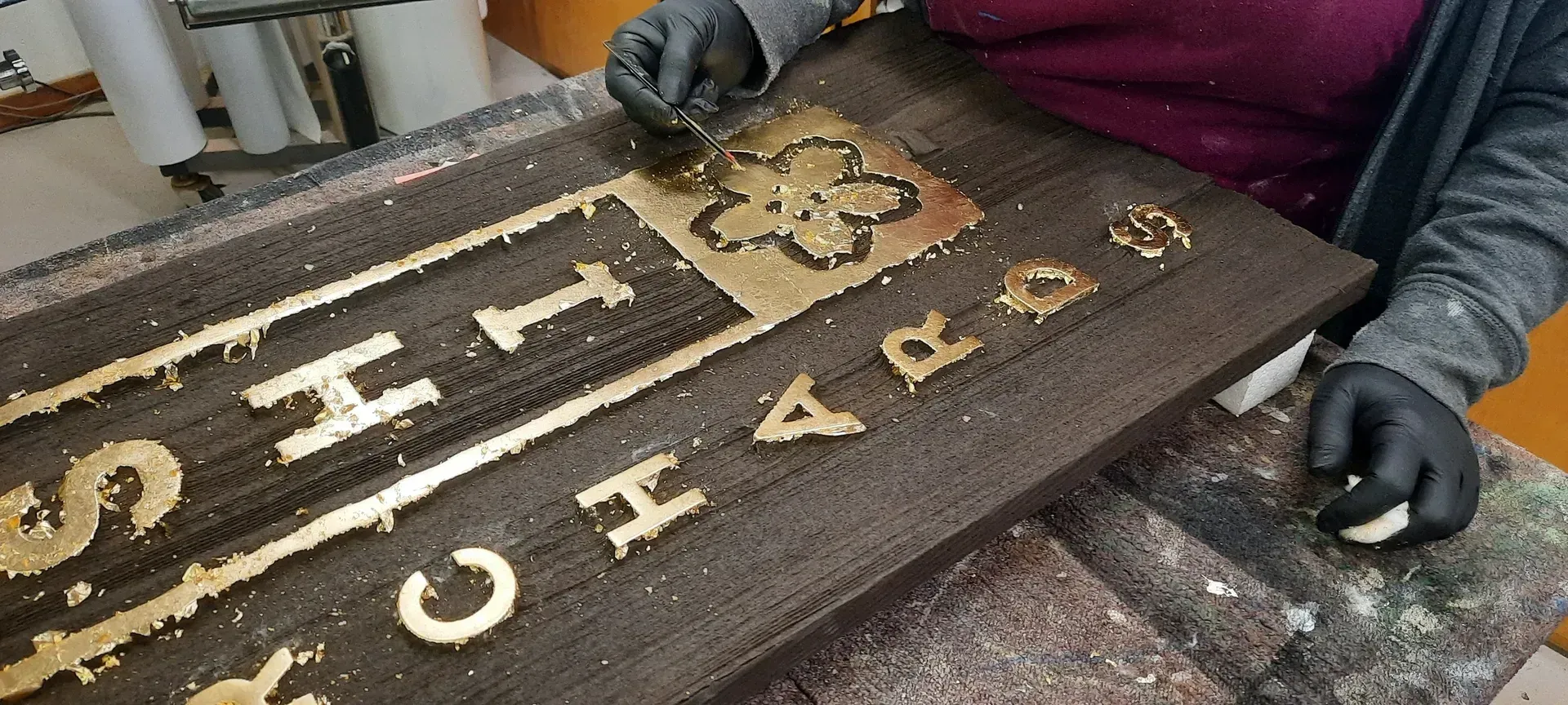 Gloved hands arranging old metal letterpress type on a workbench