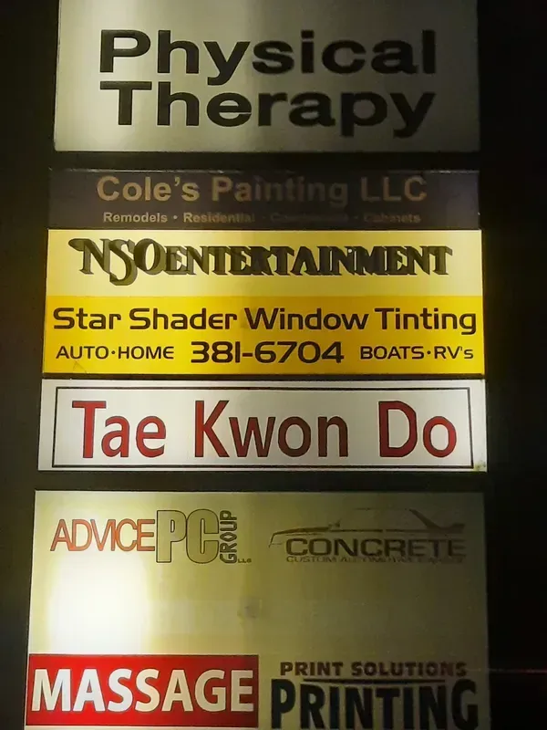 Signboard with stacked business ads: Physical Therapy, Tae Kwon Do, massage, and concrete services