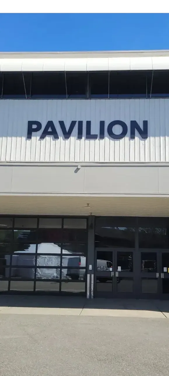 Entrance of a building with a large “PAVILION” sign above glass doors.