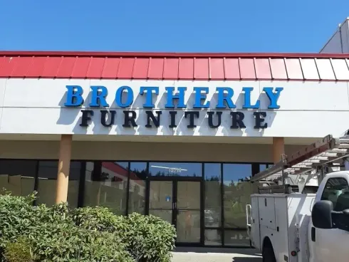 Brotherly Furniture storefront with blue and black sign under a red roof, with a white truck parked nearby