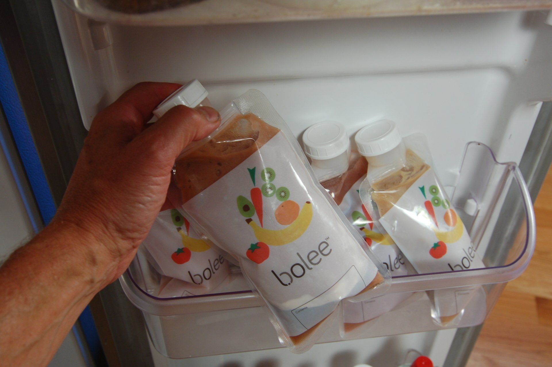 A hand taking a filled Bolee Bag out of the refrigerator