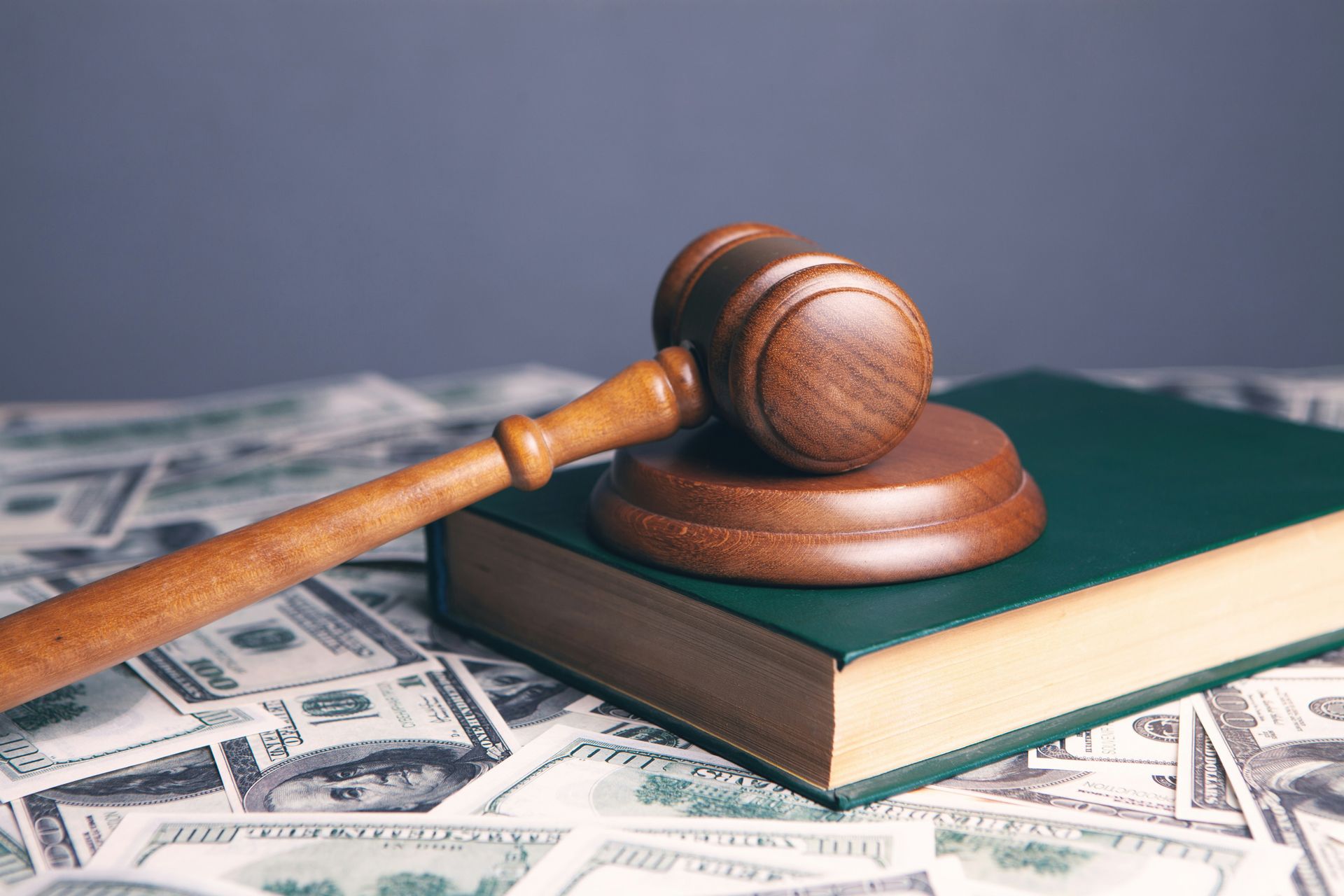 Judge’s gavel on law books over scattered dollar bills