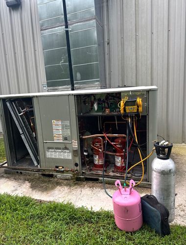 Technician holding HVAC gauge next to outdoor air conditioning unit
