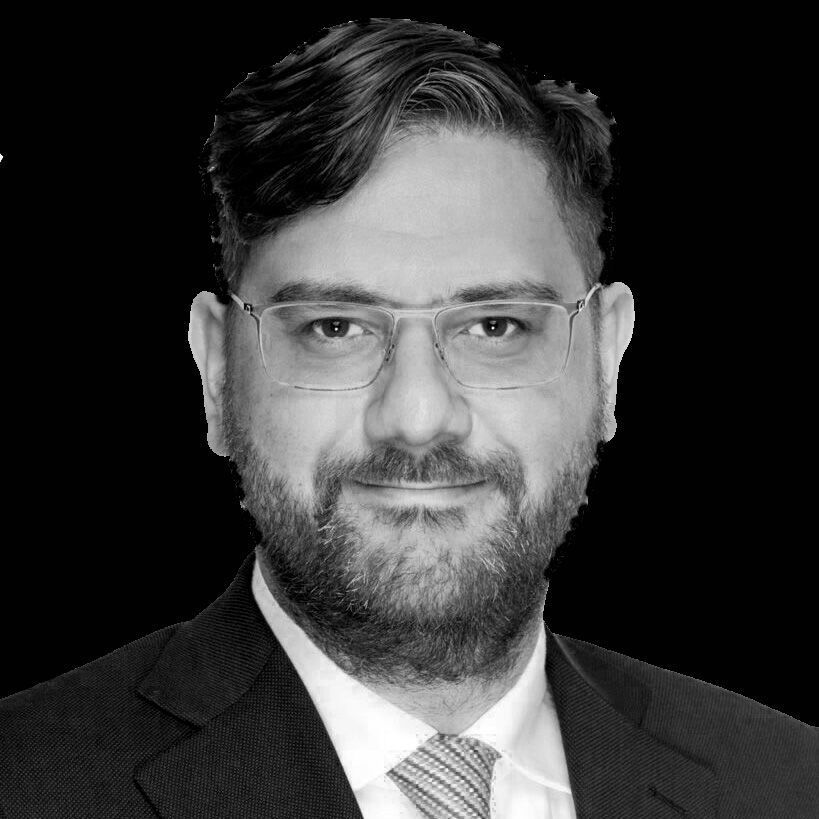 A man with a beard and glasses is wearing a suit and tie.