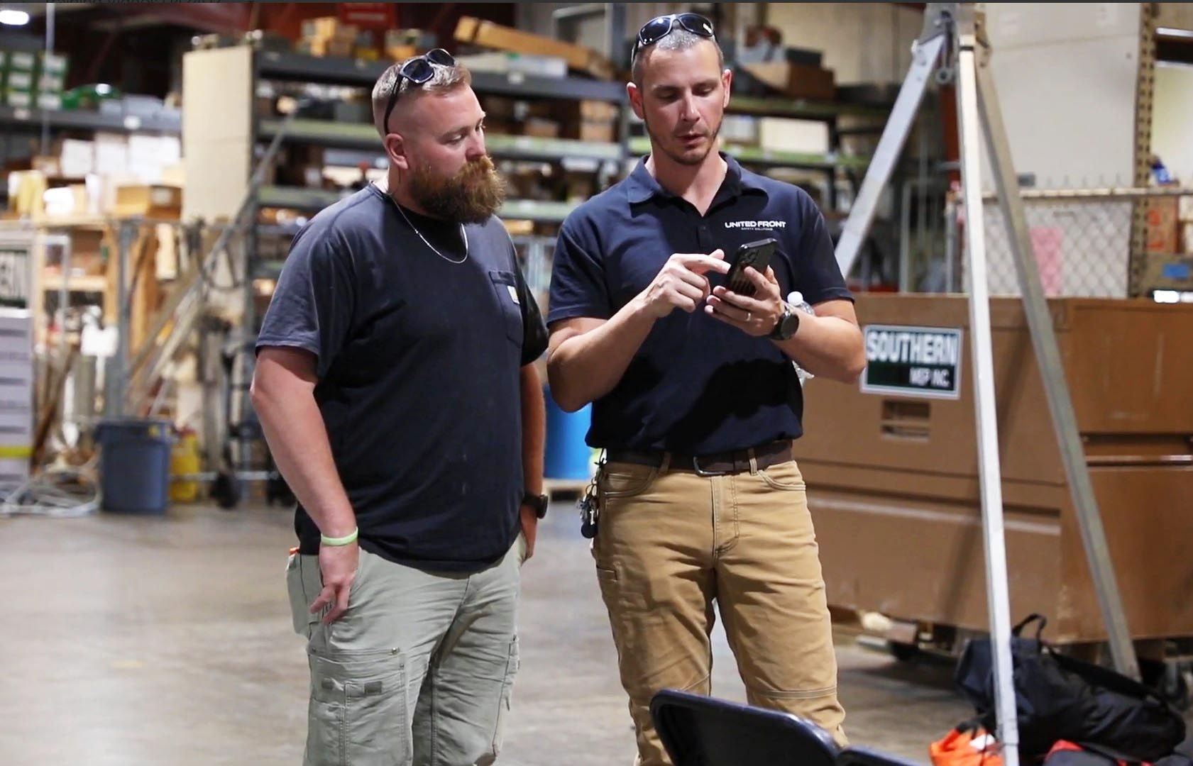 Two men discussing safety practices while looking at phone