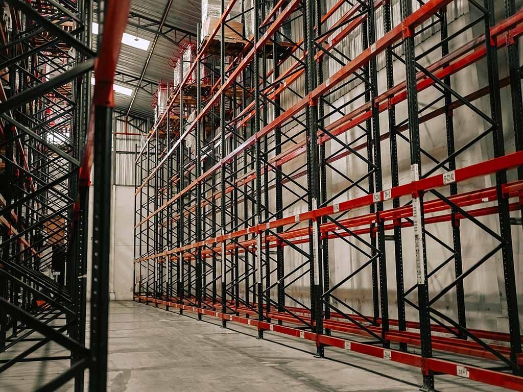 Empty warehouse aisle with tall black and red metal storage racks