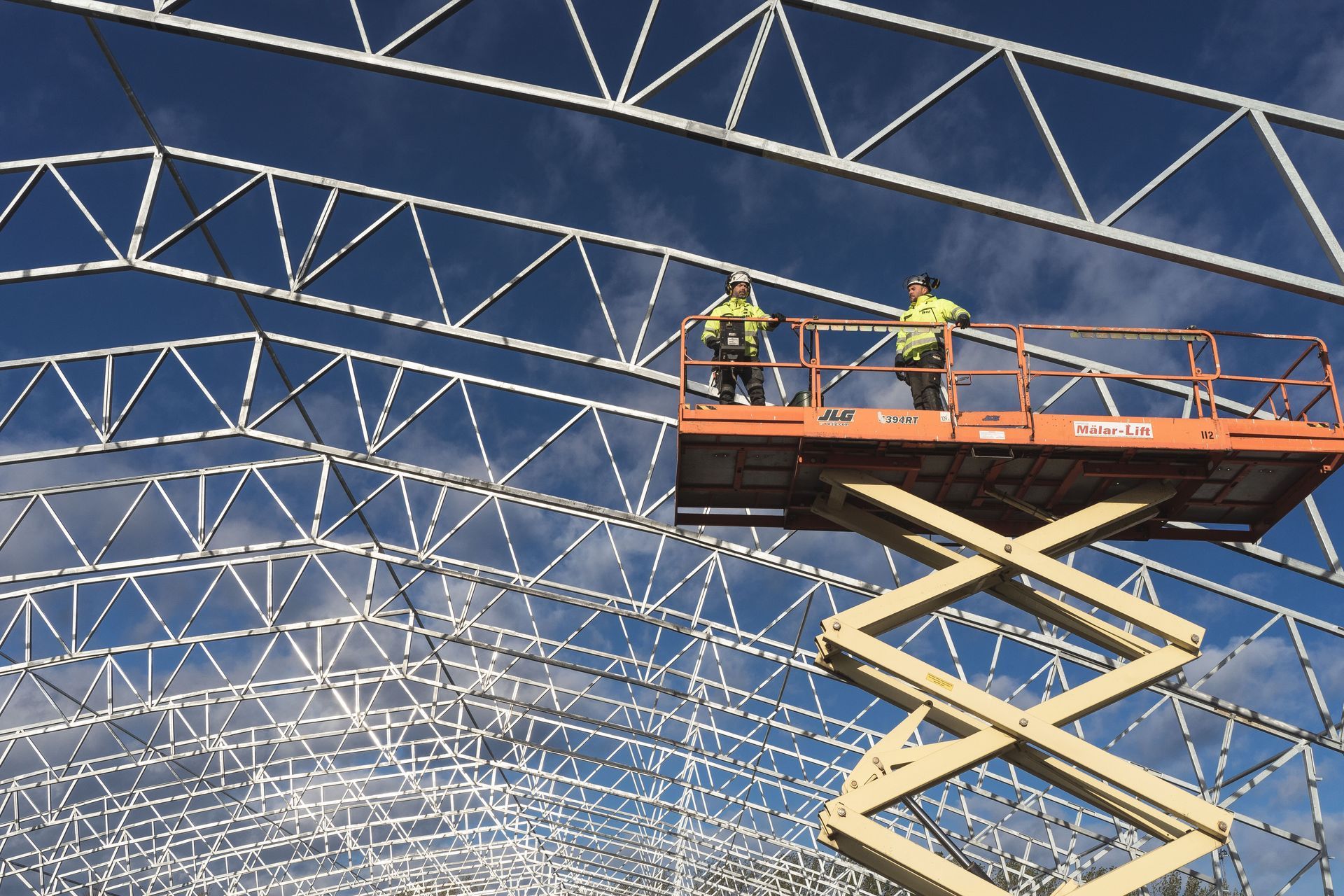 Workers operating a scissor lift on a construction site, one of five equipment types UFSS certifies