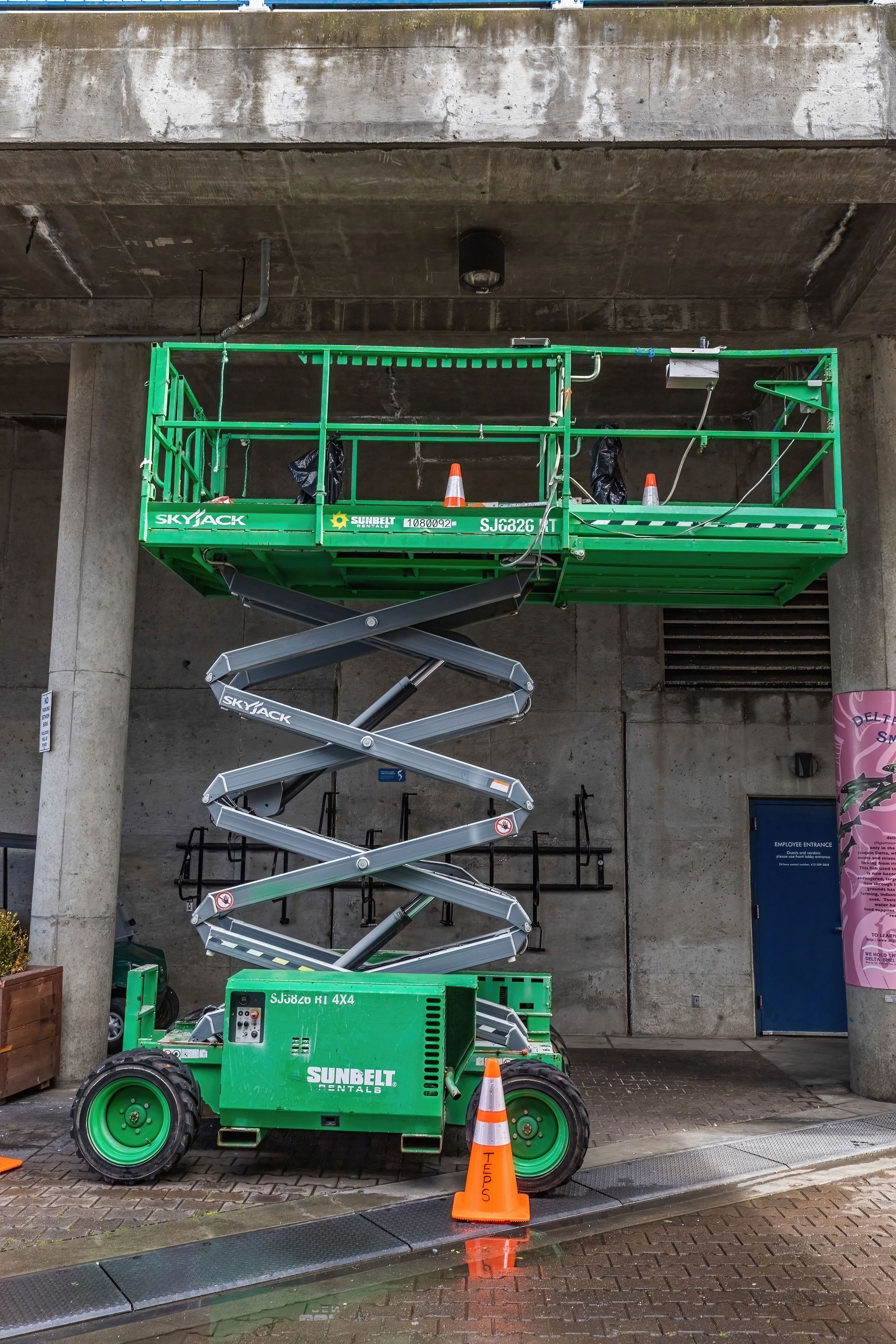 Scissor lift raised inside a concrete building, one of the lift types we certify