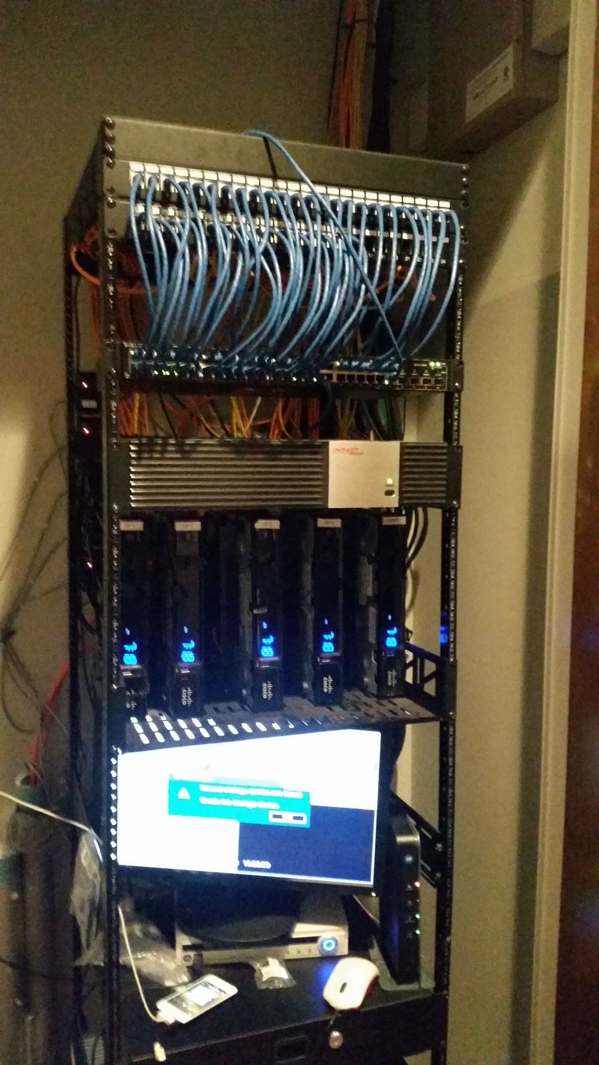 A computer is sitting on a desk in front of a server rack