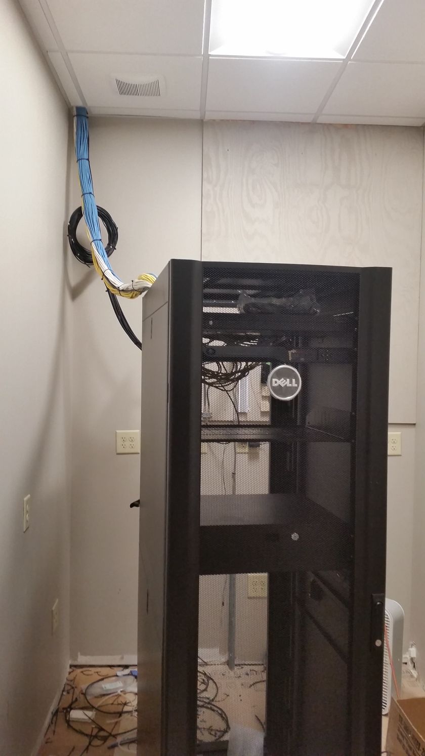 A server rack is sitting in a room next to a wall.