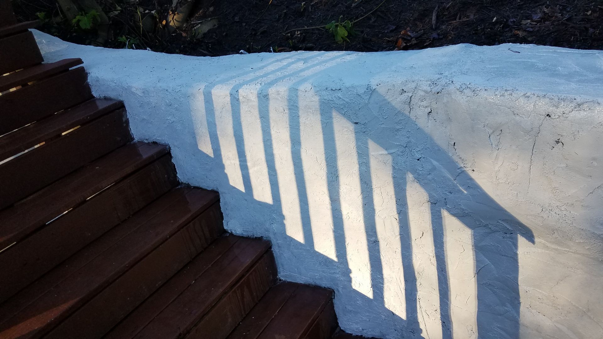 A shadow of a staircase is cast on a white wall