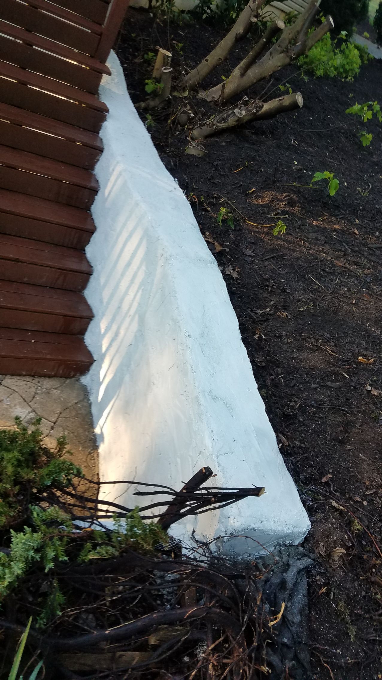 A white tarp is sitting on the ground next to a wooden fence.