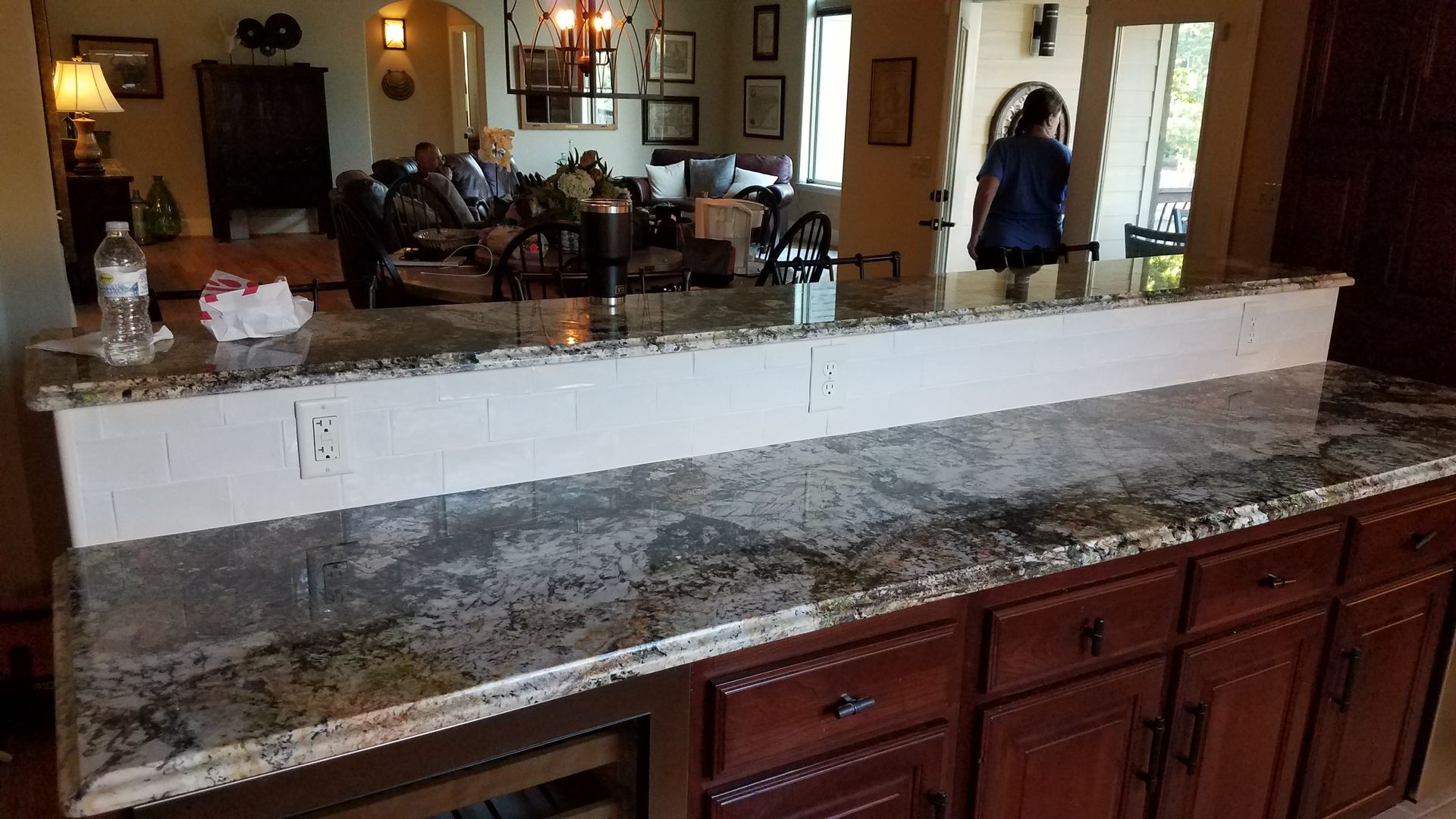 A kitchen with a granite counter top and wooden cabinets.