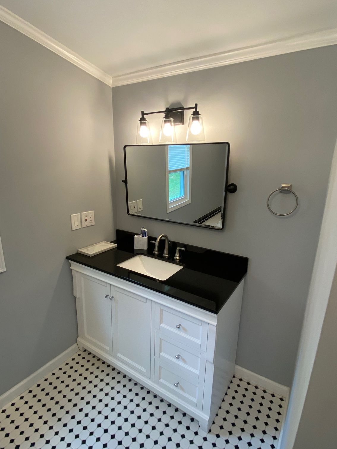 A bathroom with a sink , mirror and light fixture.