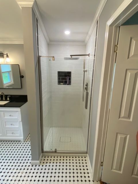 A bathroom with a walk in shower and a black and white tile floor