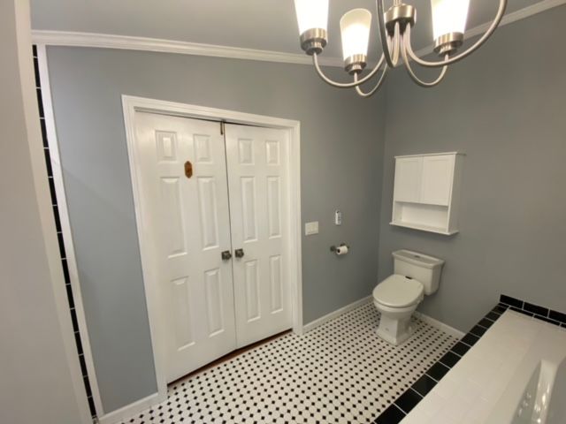 A bathroom with a toilet and a chandelier hanging from the ceiling