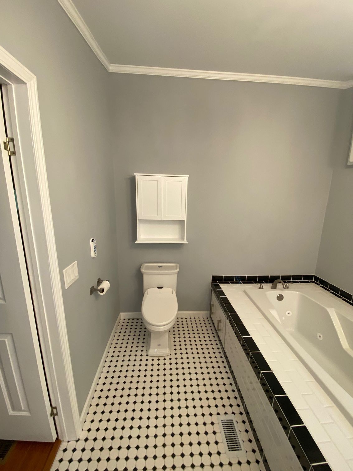 A bathroom with a toilet a bathtub and a cabinet