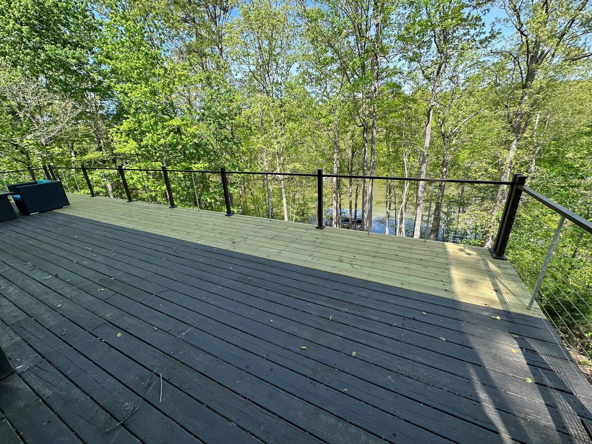 A wooden deck with a metal railing overlooking a forest.