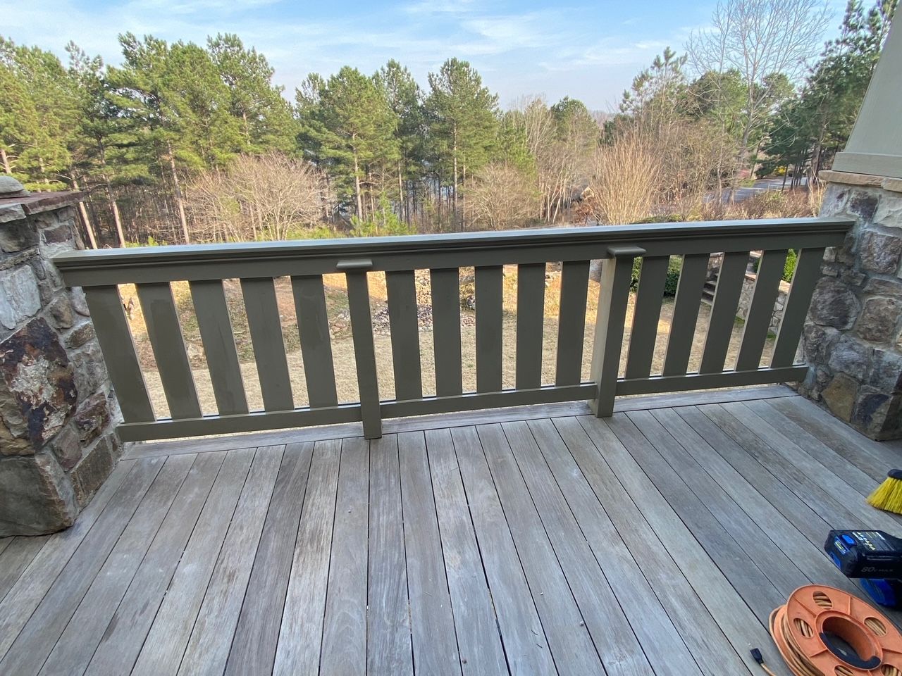 A wooden deck with a railing overlooking a forest.