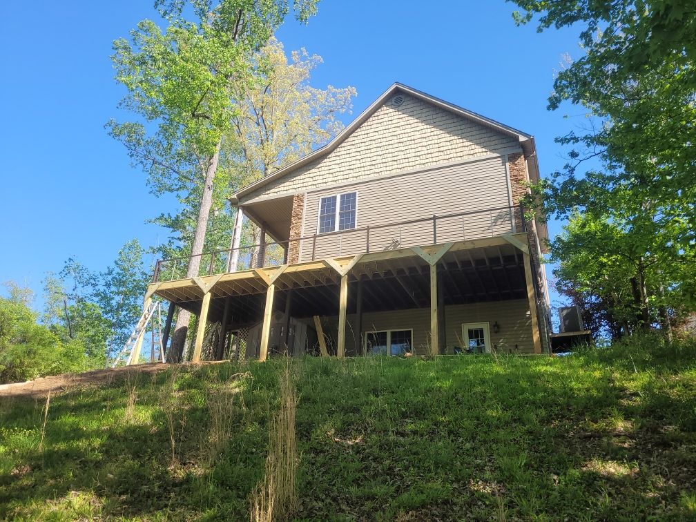 A house is sitting on top of a grassy hill surrounded by trees.