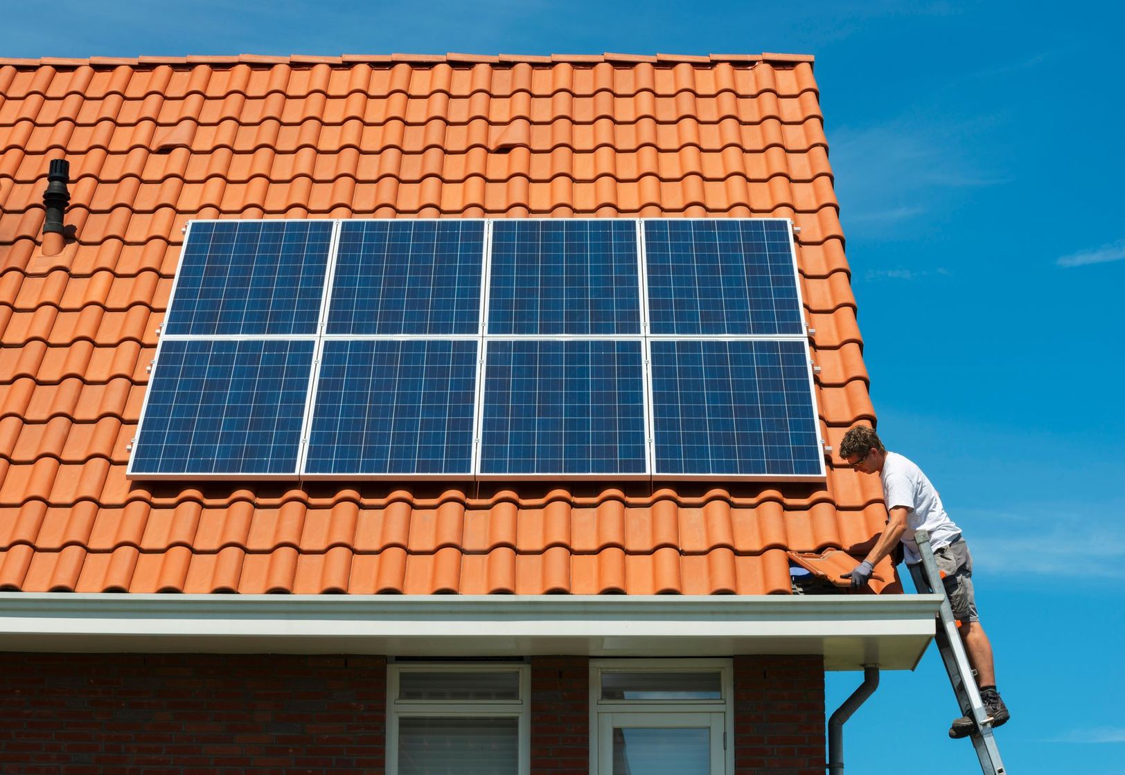 Un uomo sta installando pannelli solari sul tetto di una casa