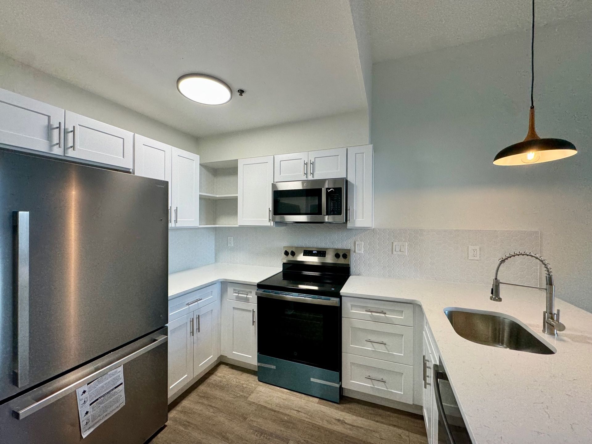 Bright modern kitchen with stainless steel appliances, white cabinets, and a white island countertop.