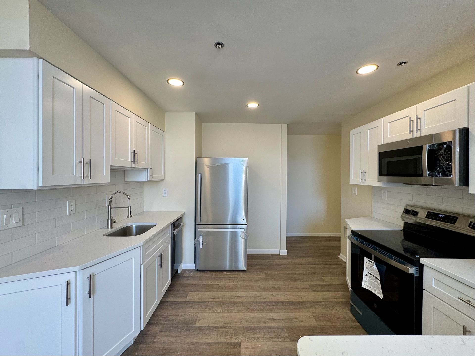 Bright modern kitchen with white cabinets, stainless appliances, and wood flooring