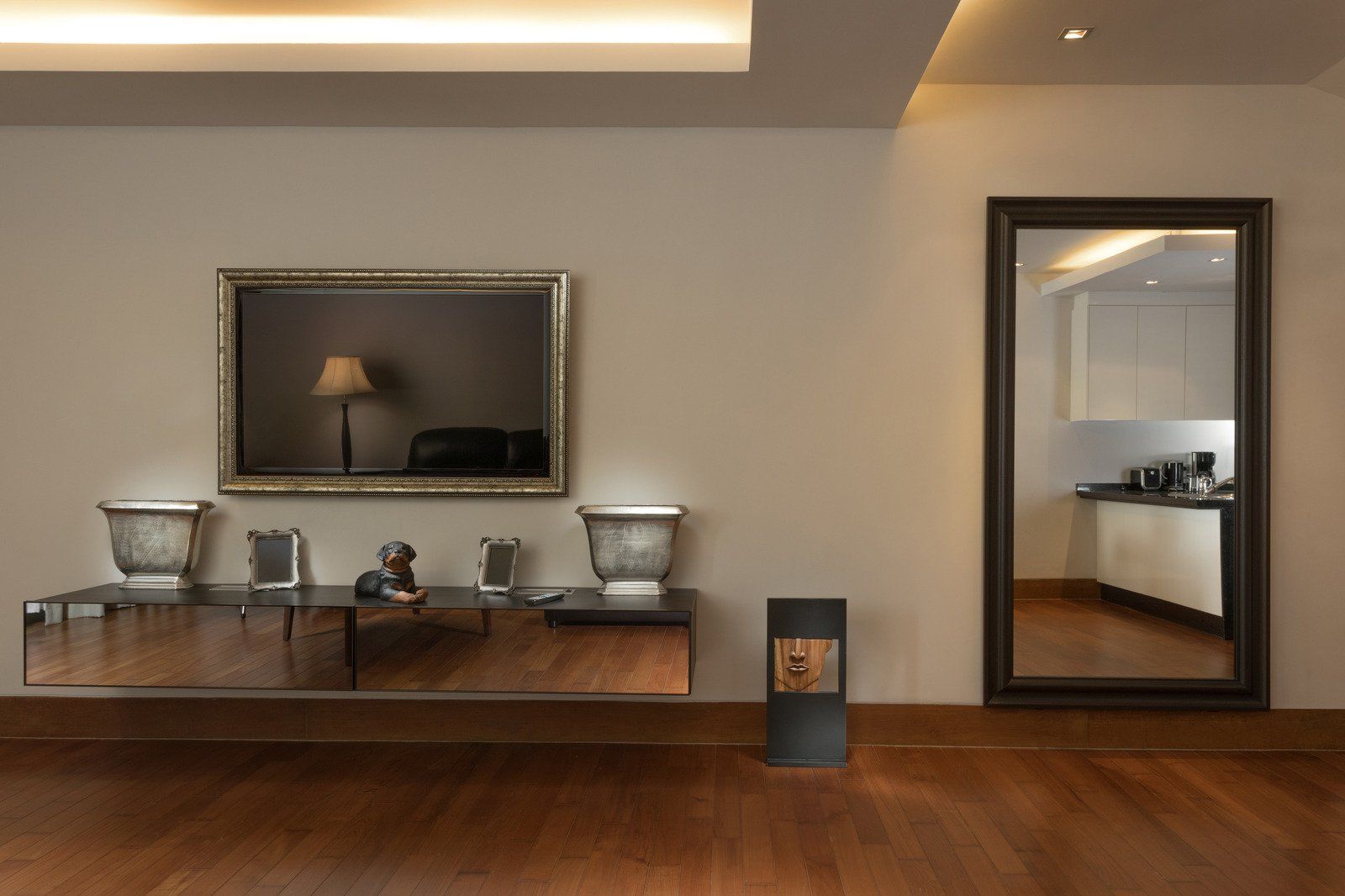 Living room with mirror, cabinet, and a standing heater against a wood floor.