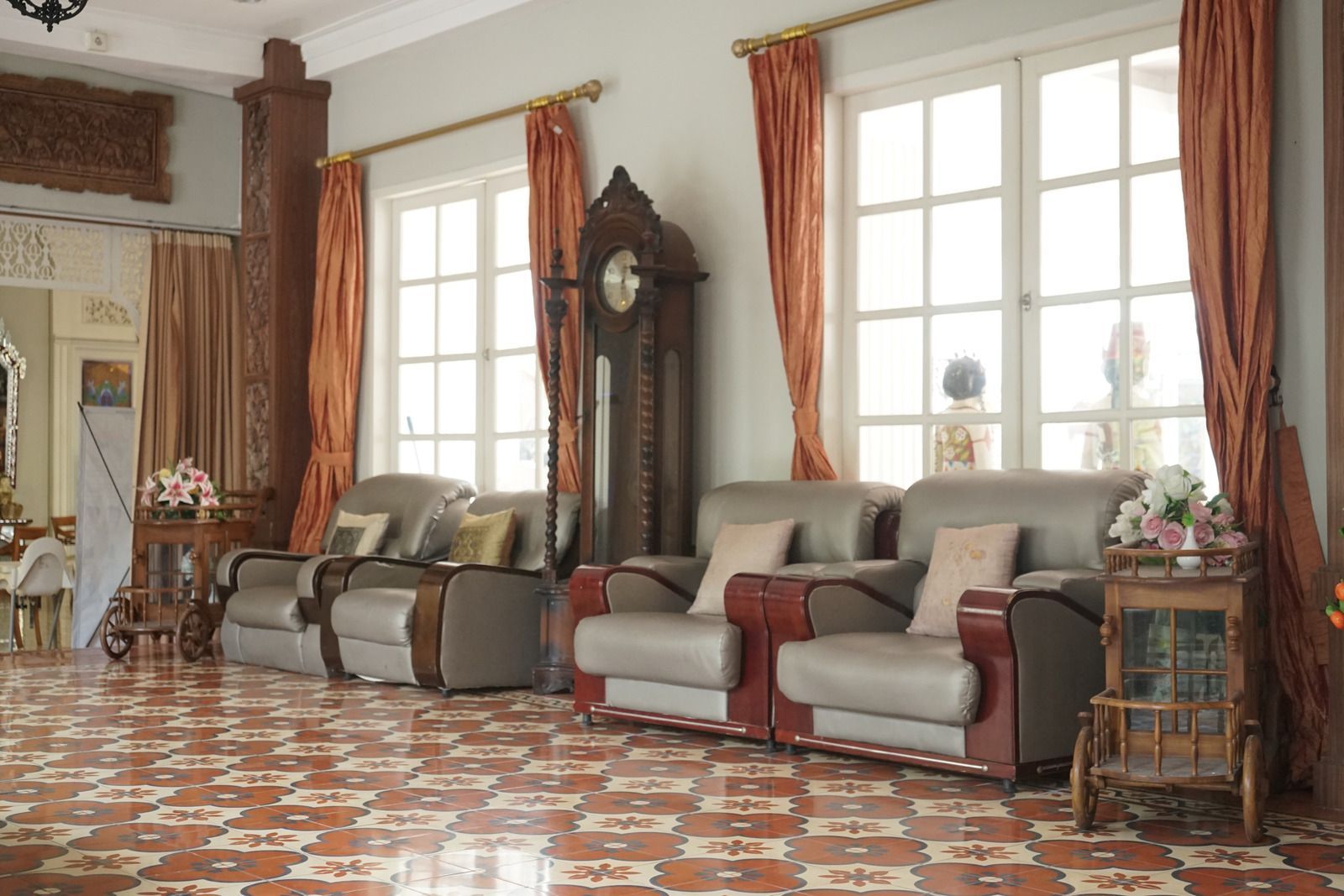 Living room with seating, large windows, curtains, and a grandfather clock.