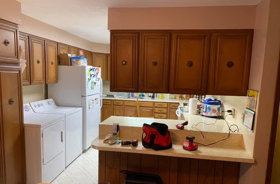 Kitchen with wooden cabinets, appliances, and a breakfast bar; brown, white, and beige hues.