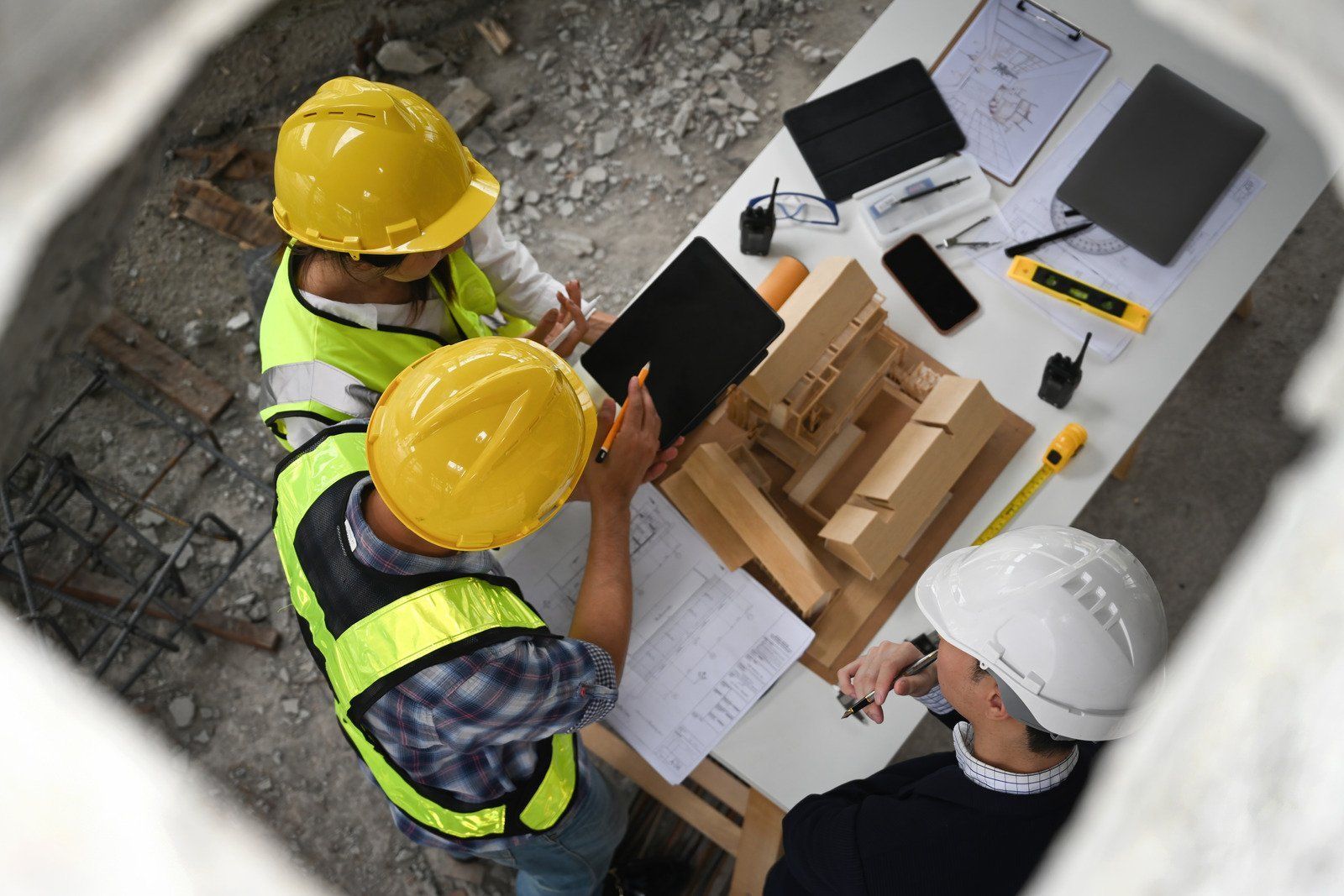 Construction workers in hard hats and vests, reviewing plans at a table.