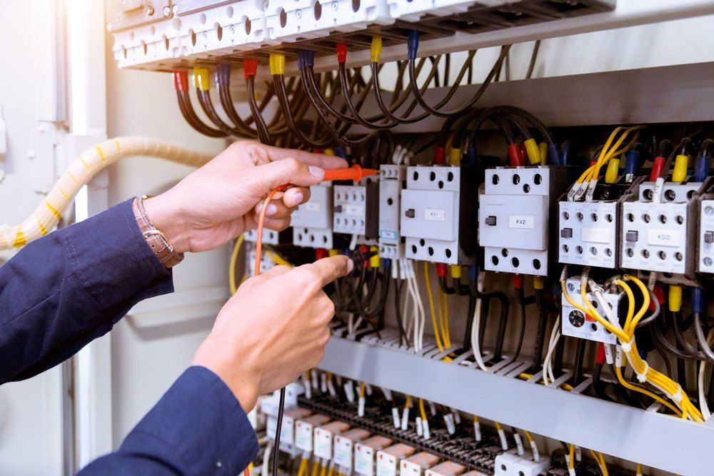 Electrician testing electrical panel wiring with a multimeter.