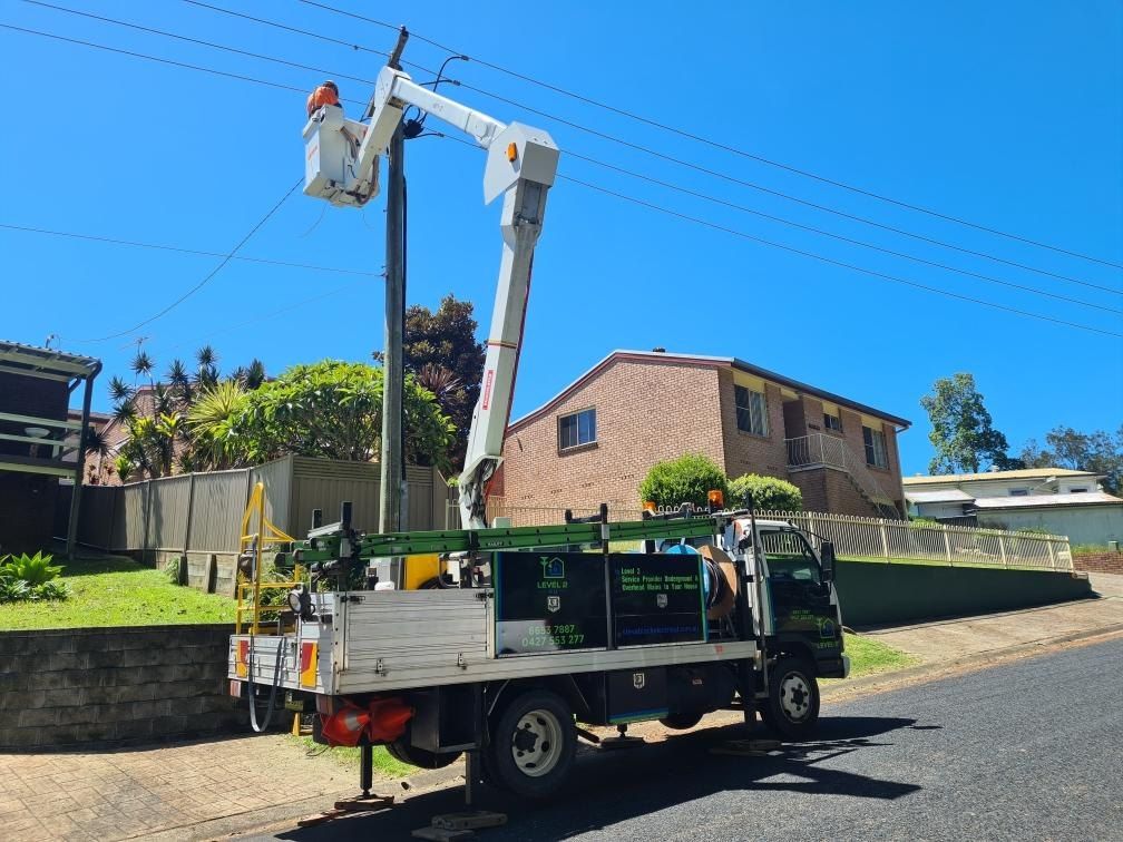 A utility truck with a raised boom working on power lines in front of a residential neighborhood.