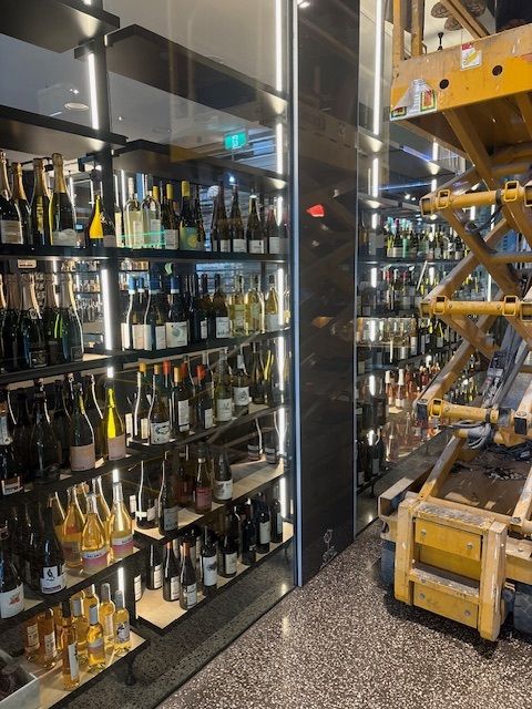 Wine bottles on shelves in a restaurant, with construction equipment visible.