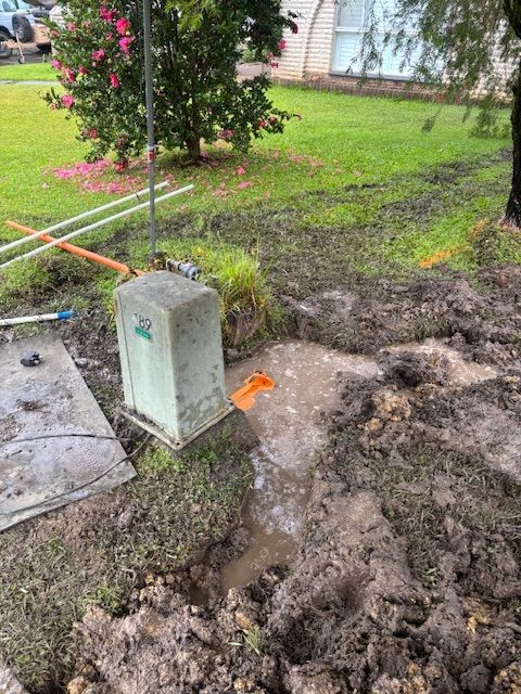 Muddy yard with open hole, utility box, and water.