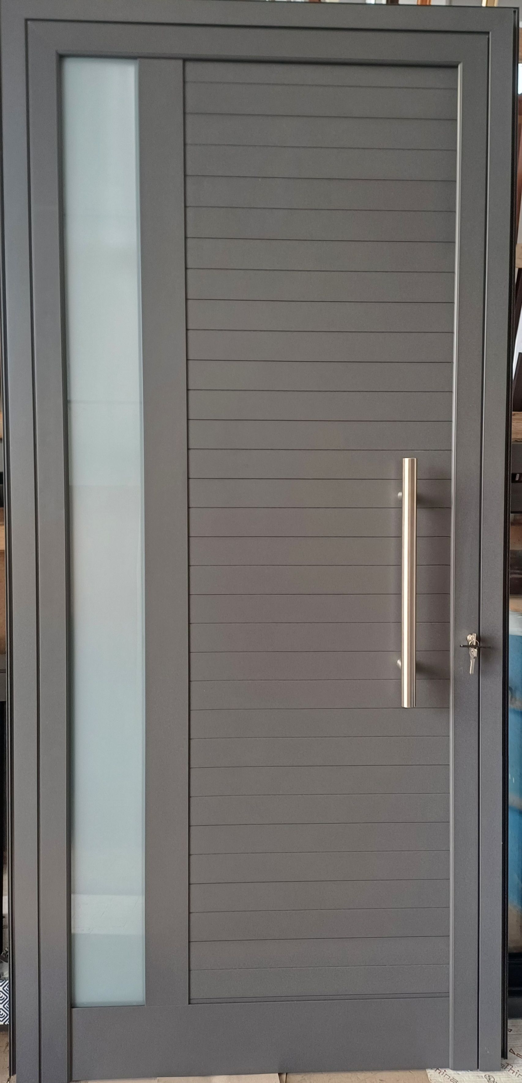 Porta d'ingresso moderna di colore grigio con pannello verticale in vetro satinato e maniglia argentata.