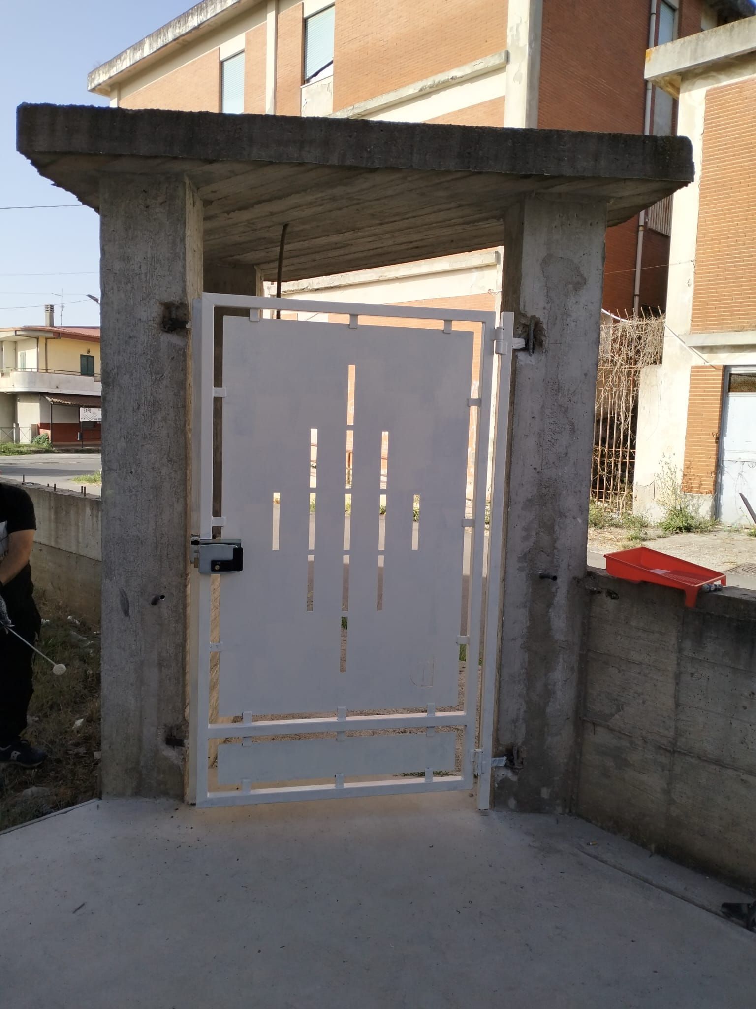 Cancello in metallo bianco sotto un arco di cemento all'ingresso di un'abitazione.