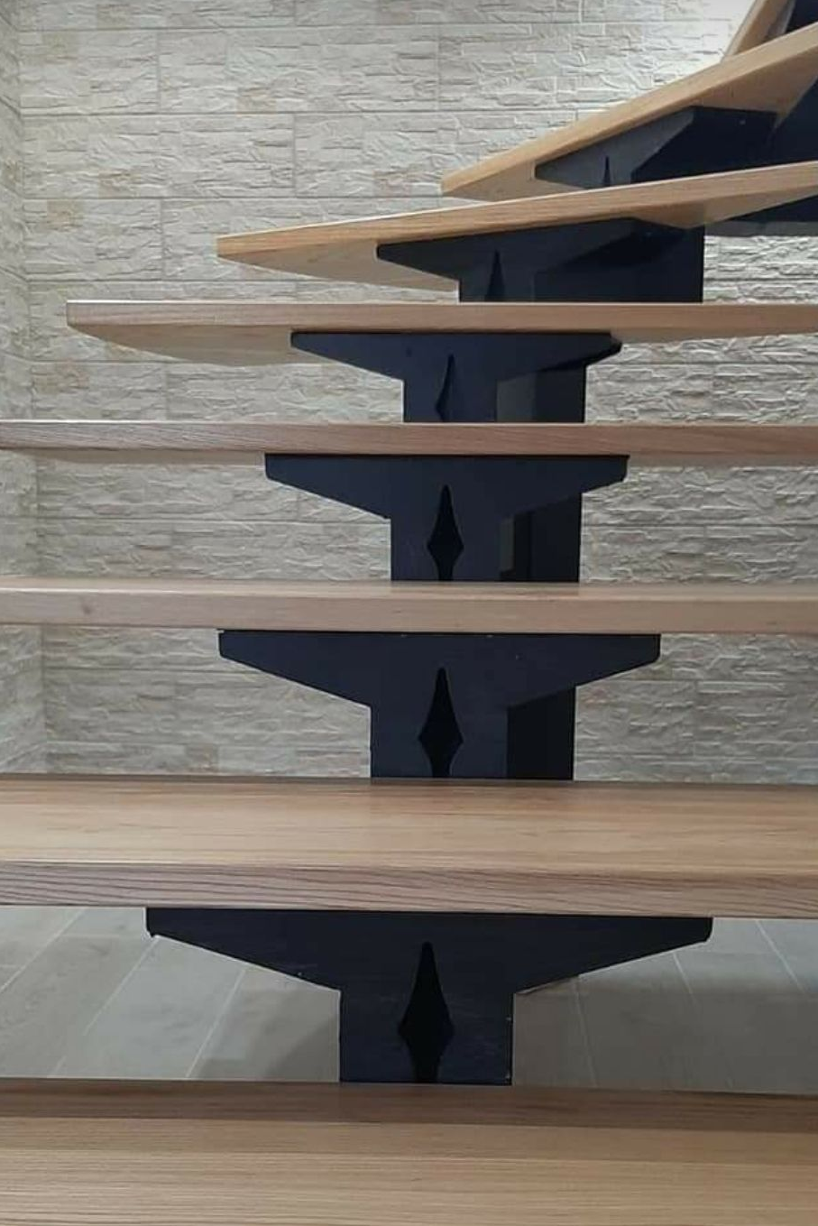 Scala in legno sospesa con supporti centrali scuri a contrasto con una parete in pietra chiara.
