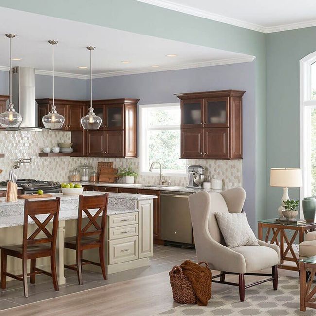 Bright kitchen with dark wood cabinets, white island, and a beige armchair by a window