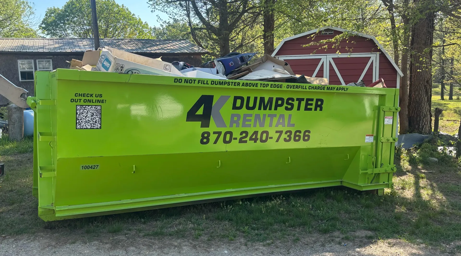 A dumpster is being pulled by a truck on a trailer.