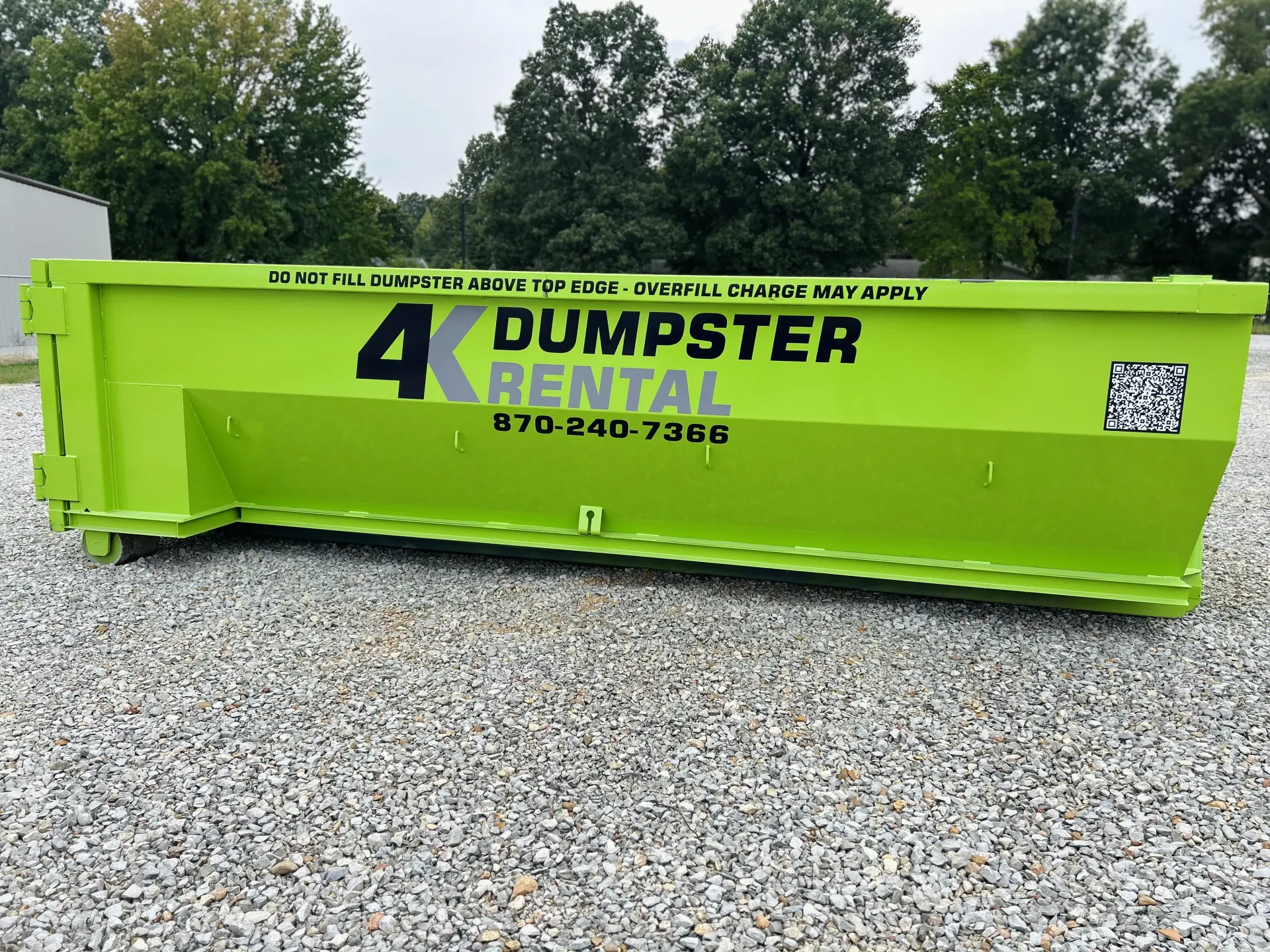 A dumpster is being pulled by a truck on a trailer.