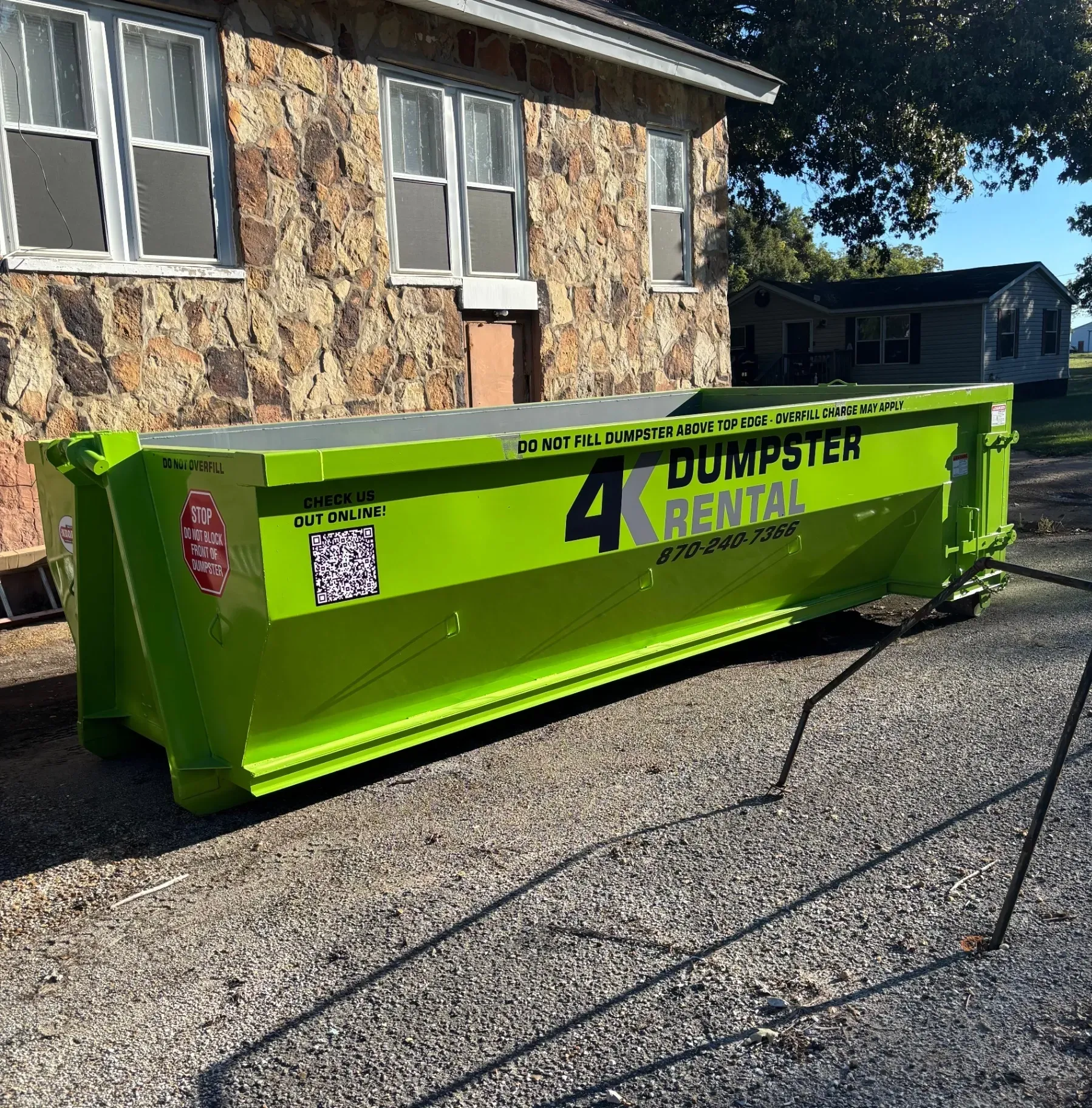 A green dumpster is parked in front of a house.
