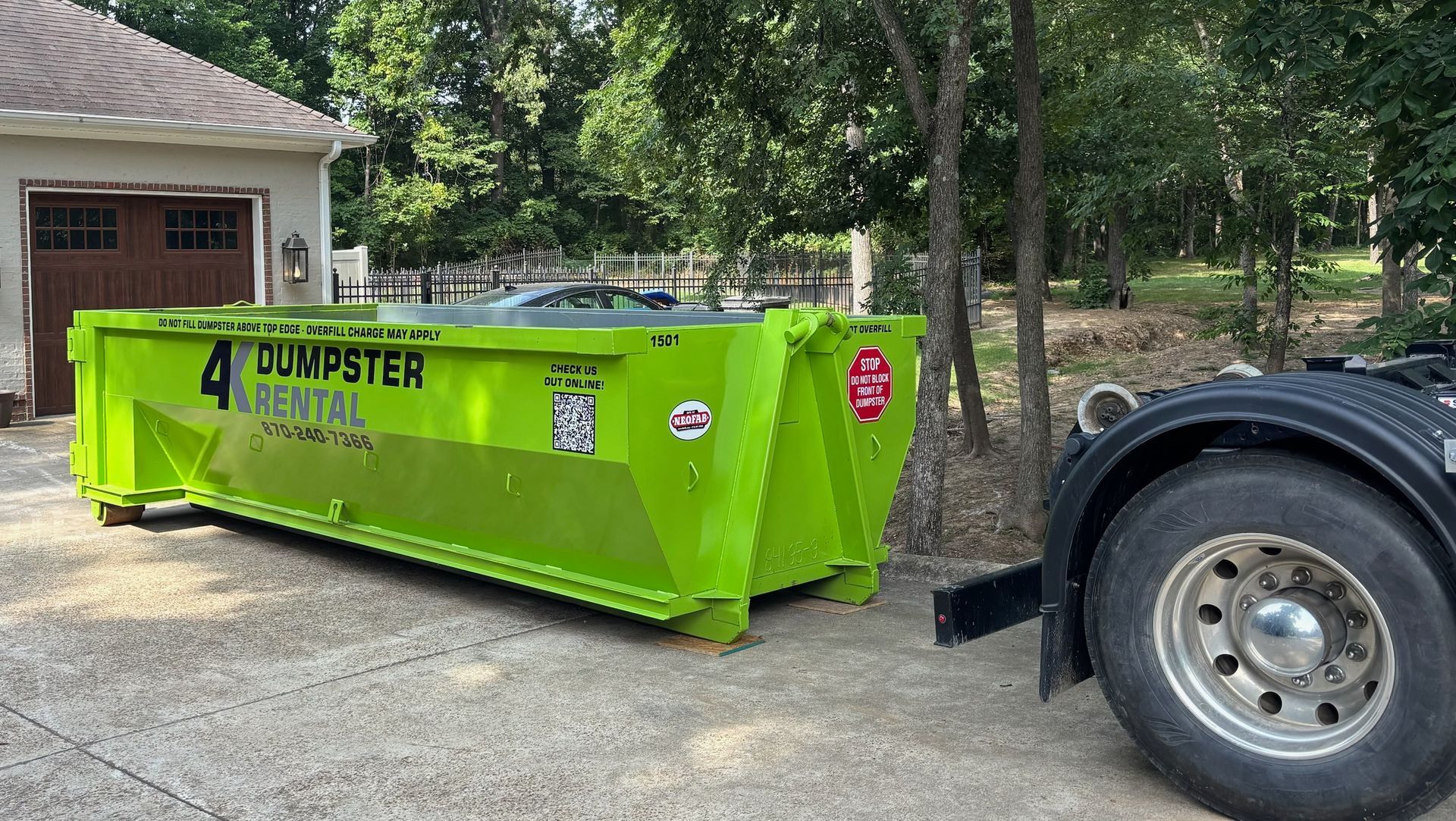 A green dumpster is parked in front of a house.