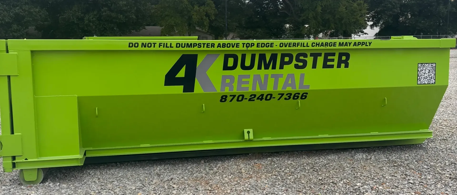 A dumpster is being pulled by a truck on a trailer.