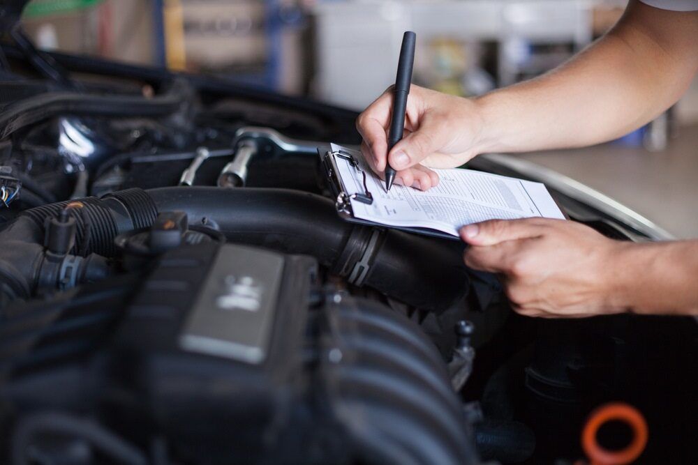 A Person is Writing on a Clipboard Under the Hood of a Car — Motortorque Automotive in South Grafton, NSW