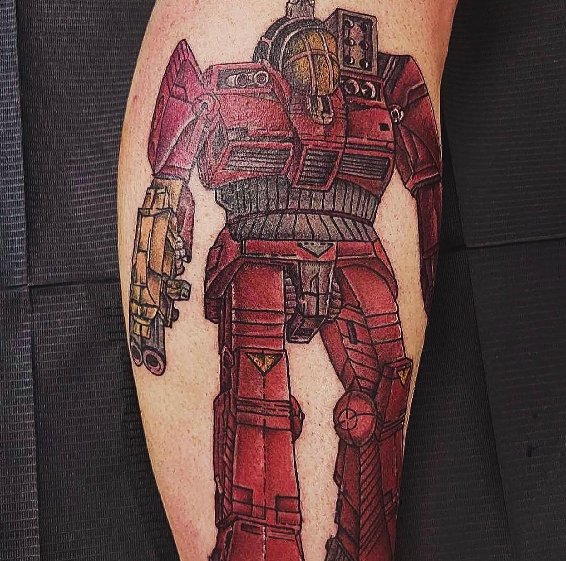 a person has a tattoo of a robot on their leg .