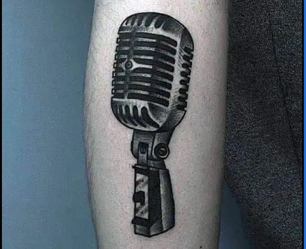 a black and white tattoo of a microphone on a person 's leg .