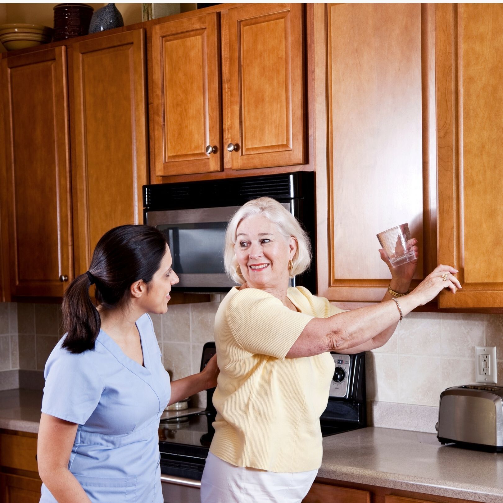 Two women are standing in a kitchen and one is holding a glass