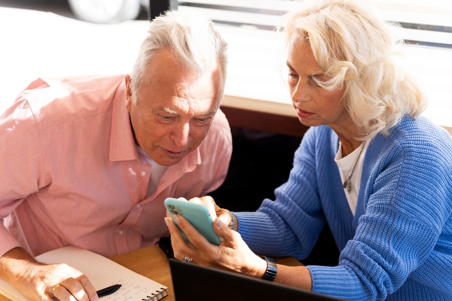 Two people on a couch looking at a smartphone together, one pointing at the screen.
